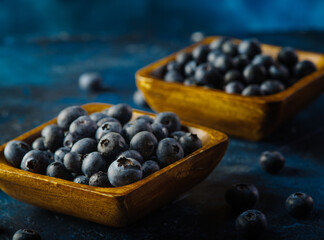 Fresh blueberries in bowls on a dark blue background. Original composition. Restaurant, hotel, cafe, food blog, cookbook. Agriculture and farming, forest.