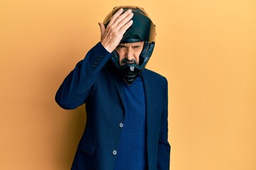 Middle age hispanic man wearing motorcycle helmet surprised with hand on head for mistake, remember error. forgot, bad memory concept.