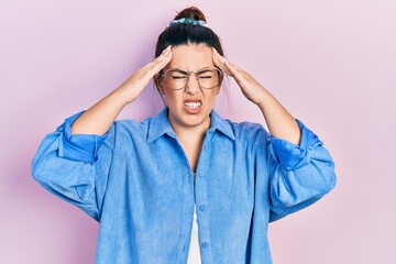Young hispanic woman wearing casual clothes and glasses suffering from headache desperate and stressed because pain and migraine. hands on head.