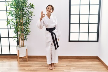 Young hispanic girl wearing karate kimono and black belt smiling positive doing ok sign with hand and fingers. successful expression. © Krakenimages.com