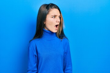 Fototapeta premium Young brunette girl wearing turtleneck sweater angry and mad screaming frustrated and furious, shouting with anger. rage and aggressive concept.