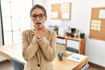 Young brunette teenager wearing business style at office shouting and suffocate because painful...