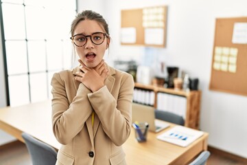 Young brunette teenager wearing business style at office shouting and suffocate because painful strangle. health problem. asphyxiate and suicide concept.