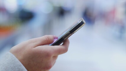 Hand of Young Caucasian Woman Using Smartphone Swiping on Screen Browsing Internet for Information	