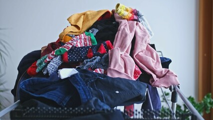 Messy Heap of Colorful Unfolded Creased Clothes Left on Laundry Dryer Rack