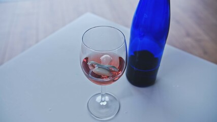 Newborn Baby Soother Sucker Floating in Glass of Rose Wine left on Table by Addicted Drinking Breastfeeding or Expecting Mother Risking Development of Fetal Alcohol Spectrum Disorder
