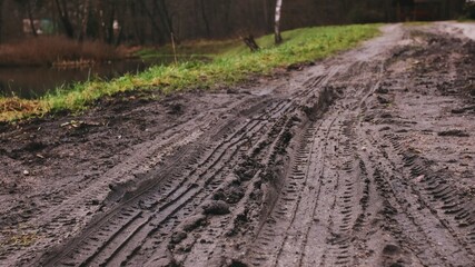Car Tire Tracks in Muddy Wet Ground Road	