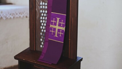 Purple Catholic Priest Stole with Embroidered Jerusalem Cross Hanging Over Grate of Simple Church...