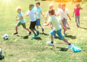 Cheerful children are jogning with ball on the playground. High quality photo