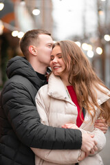 Naklejka premium A close-up photo of a girl and her boyfriend hugging and happily spending time together. The concept of light valentine's day, gifts
