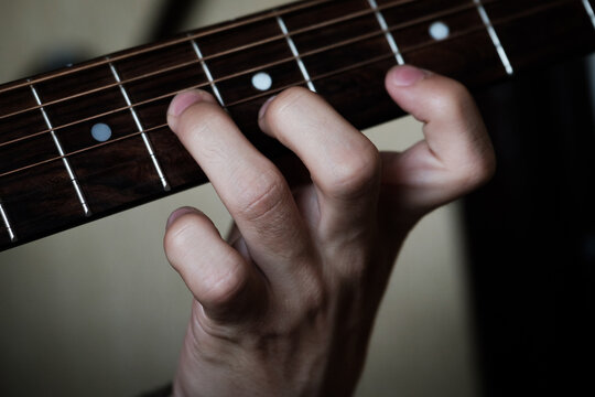 Hand playing masterly on a guitar.