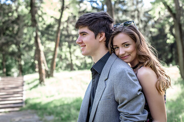 Fototapeta premium laughing happy girl in arms of loving guy. handsome young guy in park on a walk with a friend in spring.