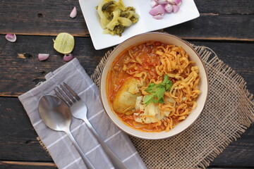 Thai Food, Northern Style Curried Noodle Soup or what we call in thai "Khao Soi" served in art style patterned bowl. on black wooden table