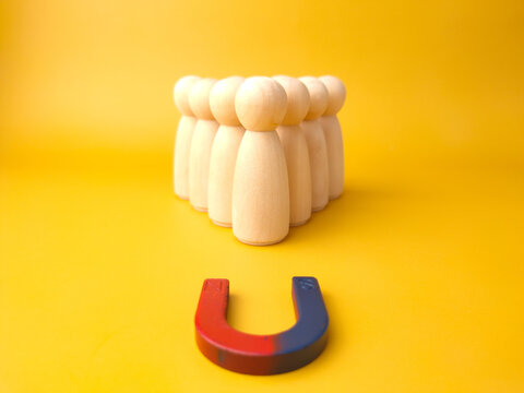 Wooden figures of people and a magnet. Team management concept. Human resources. Promote. Choosing a new leader and hiring employees to work. Headhunting services. Employee dismissal.