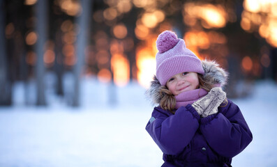 A little girl at sunset in the forest is smiling 