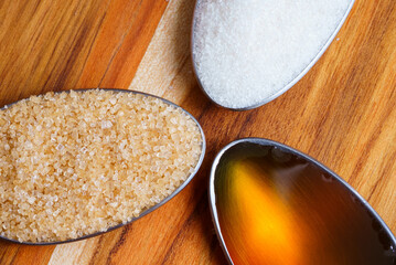 Close up top view image of spoons with honey, brown sugar and white sugar - Different kinds of...