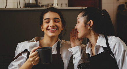 Close-up of a portrait of two young and beautiful business women sitting with coffee mugs chatting in a good mood while relaxing while working in a small business coffee shop.