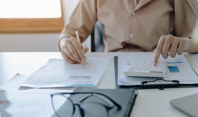 Close up Business woman using calculator and laptop for do math finance on wooden desk in office and business working background, tax, accounting, statistics and analytic research concept