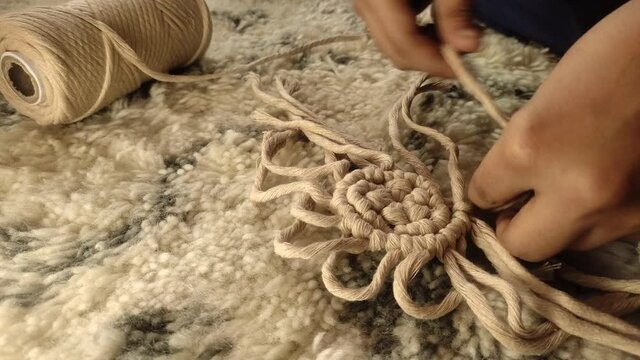 woman knotting beautiful macrame by hand as hobby.