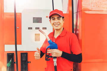 Portrait handsome male asian worker wearing a red uniform stands with a gas nozzle serving...