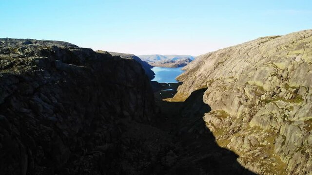 Aerial shot of a large gorge with a big fjord in the background, sunny day in norway