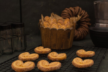 Cookies in a wooden bowl and a cup of coffee on a black background