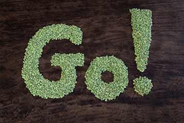 The word go formed with dried, green split peas on a rustic, wooden table