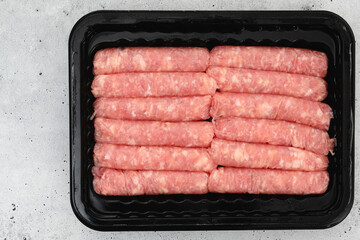 Chicken breakfast sausages in black plastic container close up, flat lay, copy space