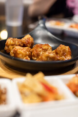Fried chicken with soy sauce served on the black hot plate with kimchi on table. Traditional Korean Crispy Chicken in a modern Korean restaurant.