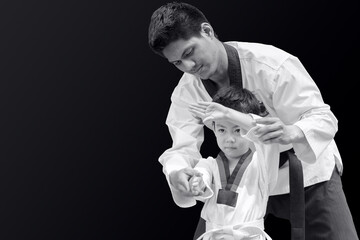 Taekwondo master black belt teaching kid to fight guard on black background