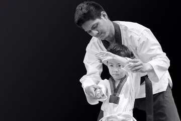 Afwasbaar fotobehang Taekwondo master black belt teaching kid to fight guard on black background © Quality Stock Arts