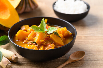 Thai spicy pumpkin curry soup with pork on wooden table