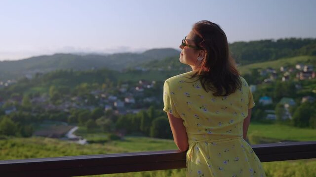 observation deck in modern eco hotel in mountains, woman is enjoying view in summer