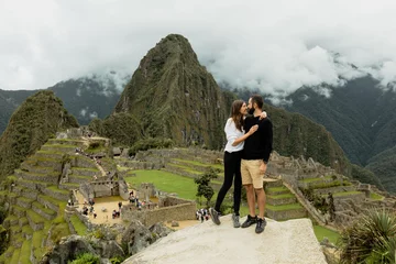 Foto op Plexiglas Machu Picchu Happy young couple stands on the rock with Machu Picchu on the background, Cusco, Peru