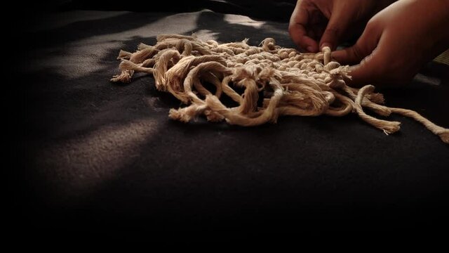 woman knotting beautiful macrame by hand as hobby. closeup video in 4k.
