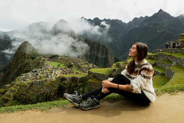 A young woman sitting on the natural terrace with the mountains on the background - obrazy, fototapety, plakaty