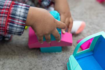 Child playing with bricks at home to construct a toy