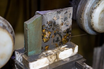 Sawing of the Pallasite iron-stone meteorite with a thin diamond thread. Inclusions of the yellow...