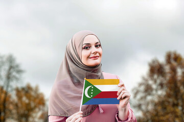 Muslim woman in hijab holds flag of Comoros
