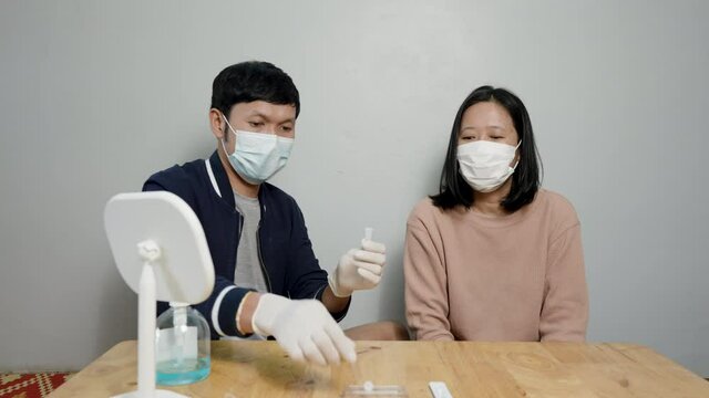 4K, Asian couple Drop liquid on COVID-19 sample test strips, coronavirus epidemic prevention concept, rapid antigen test kit to test yourself, COVID-19 epidemic at home.