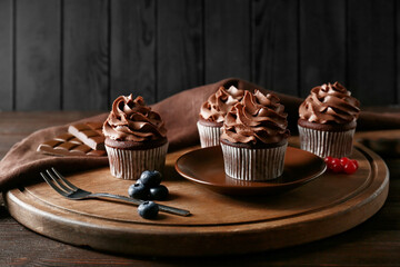 Tasty chocolate cupcakes with berries on table