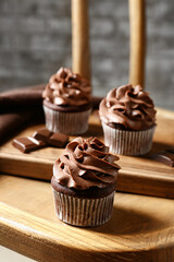 Tasty chocolate cupcakes on wooden chair