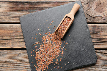 Scoop with flax seeds on wooden background
