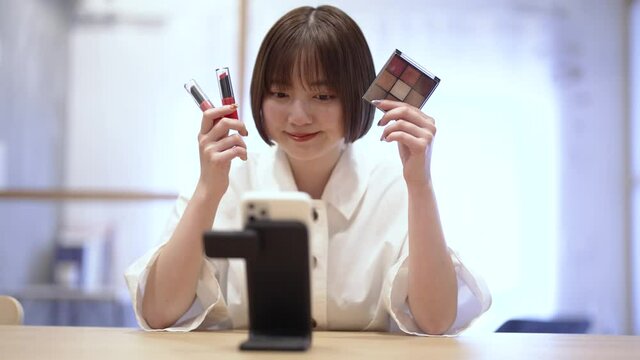 スマートフォンを使ってコスメグッズを紹介する女性