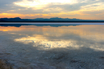 The sun shines behind the clouds above the lake