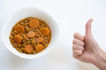 Hand with thumbs up next to vegan plate of lentils