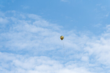 Fototapeta na wymiar A golden balloon flew under the blue sky and white clouds