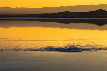 The golden glow of the sky over the mountains and the salt lake