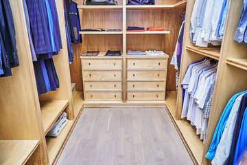 Stylish walk in closet with furniture of maple solid and veneer wood for clothes storage with crown molding in apartment