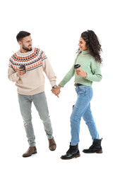 Fototapeta premium Happy young couple in warm sweaters and with coffee on white background